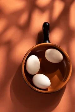 Handmade ceramic plates with home eggs on brown background. Terracotta objects,  Stock Photos