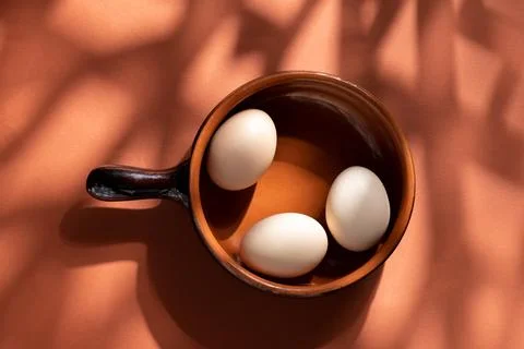 Handmade ceramic plates with home eggs on brown background. Terracotta objects,  Stock Photos