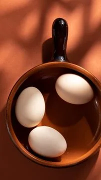 Handmade ceramic plates with home eggs on brown background. Terracotta objects,  Stock Photos