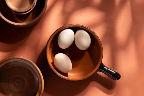Handmade ceramic plates with home eggs on brown background. Terracotta objects,  Stock Photos