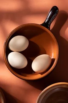 Handmade ceramic plates with home eggs on brown background. Terracotta objects,  Stock Photos