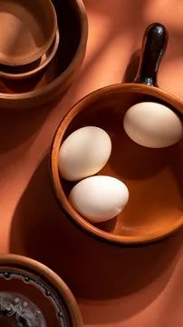 Handmade ceramic plates with home eggs on brown background. Terracotta objects,  Stock Photos