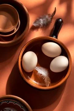 Handmade ceramic plates with home eggs on brown background. Terracotta objects,  Stock Photos