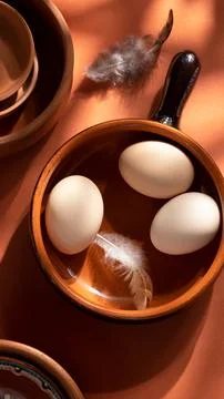 Handmade ceramic plates with home eggs on brown background. Terracotta objects,  Stock Photos