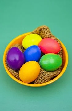 Handmade Colored Easter Eggs in Decorative Orange Bowl Over Blue Background Stock-Fotos