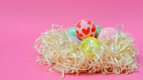 Handmade colorful Easter eggs decorated by a child in the nest on a pink Foto stock