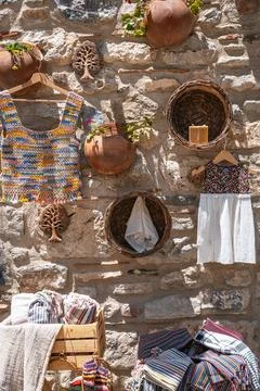 Handmade crafts and textiles on a rustic stone wall Stock Photos