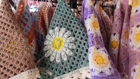 Handmade crochet items on display at a market in a vibrant setting Stock Footage 345385228