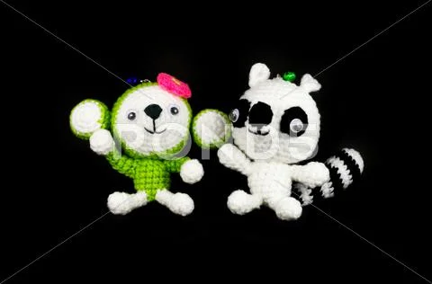 Handmade crochet monkey and raccoon doll on black background Stock Photos