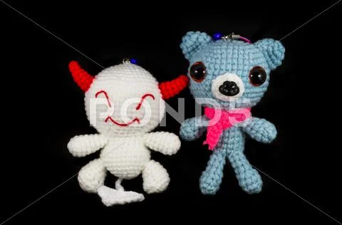 Handmade crochet white devil and dog doll on black background Stock Photos