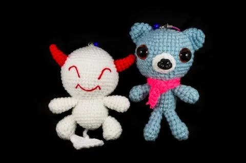 Handmade crochet white devil and dog doll on black background Stock Photos