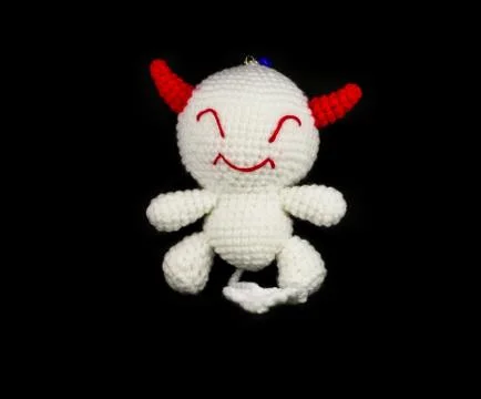 Handmade crochet white devil with red ear doll on black background Stock Photos