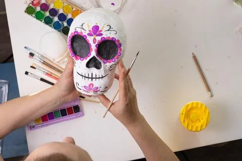 A handmade decorative sugar skull in progress on a craft table, showing the p Stock Photos