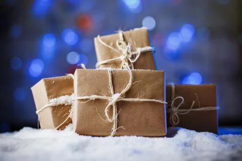 Handmade gift boxes from craft paper over snowy wooden table in blue light. Stock Photos