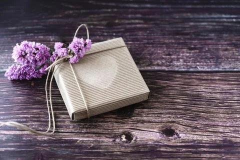 Handmade gift concept. Craft paper recycle gift box with flowers on wooden ta Stock Photos