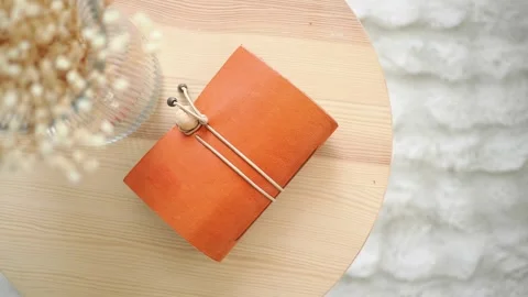 Handmade leather notebook on a wooden table in a bright room Stock Footage 340443194
