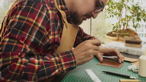 Handmade man hobbies. Young leather craftsman creates bag product for e-commerce Stock Footage 140519906