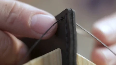 The handmade master creates a black leather wallet with his own hands with a  스톡 동영상 81931860