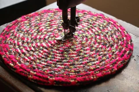 A handmade mat is under a machine to be finished. Stock Photos