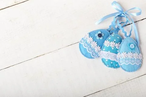 Handmade patchwork blue felt sewed easter eggs on white wooden table Foto stock