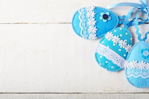 Handmade patchwork blue felt sewed easter eggs on white wooden table Stock-Fotos