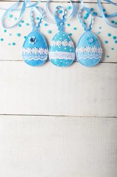 Handmade patchwork blue felt sewed easter eggs on white wooden table Stock-Fotos