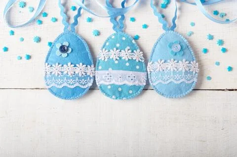 Handmade patchwork blue felt sewed easter eggs on white wooden table Stock Photos