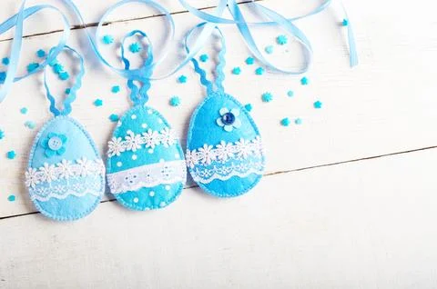 Handmade patchwork blue felt sewed easter eggs on white wooden table Stock-Fotos