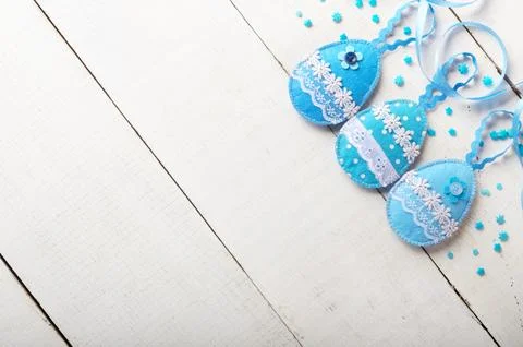 Handmade patchwork blue felt sewed easter eggs on white wooden table Stock-Fotos