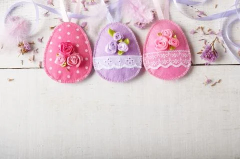 Handmade patchwork pink and lilac felt easter eggs on white wooden table Foto stock