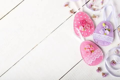Handmade patchwork pink felt easter eggs on white wooden table Stock-Fotos