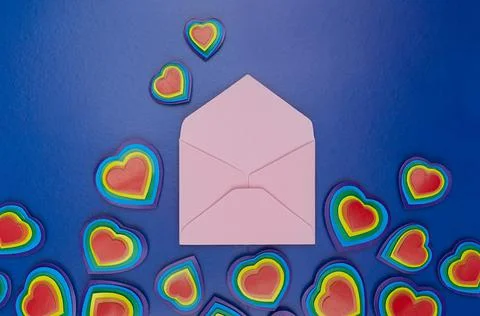 Handmade rainbow hearts with open blank pink envelope as love note on dark bl Stock Photos