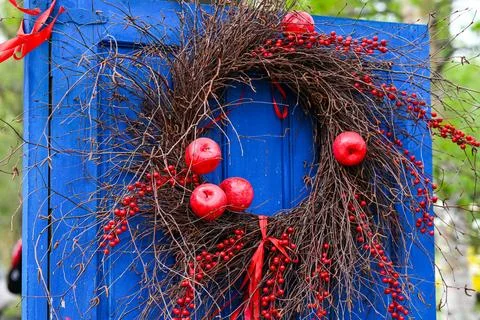 Handmade rustic wreath made of dry twigs red apples and berries hanging on .. Stock Photos