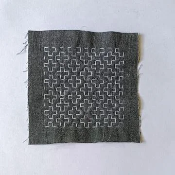 Handmade sashiko pattern on indigo fabric square. Stockfoto's