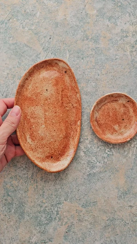 Handmade small ceramic oval plates rotating in hands Video stock 324531485