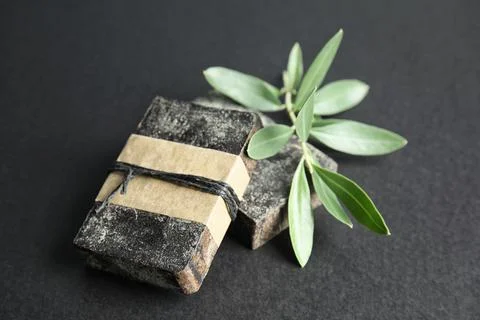 Handmade soap bars and olive twig on black background Foto stock
