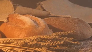 Handmade tasty bread lying on burlap on the wooden table with flour, wheat and Stock Footage 86019310