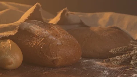 Handmade tasty bread lying on burlap on the wooden table with flour, wheat and Video stock 86019466
