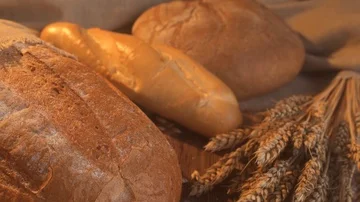 Handmade tasty bread lying on burlap on the wooden table with flour, wheat and Stock Footage 86019599