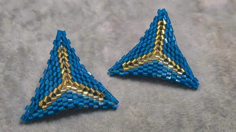 Handmade triangle earrings made of beads and glass beads, blue and gold Stock Photos