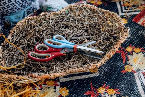 Handmade weave basket with scissors on table. Craft workshop. Stock Photos