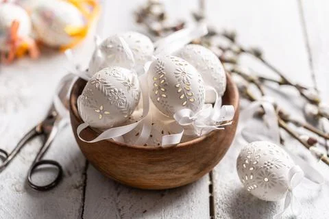 Handmade white easter eggs with willow catkins in a wooden bowl on wooden tab Stock Photos