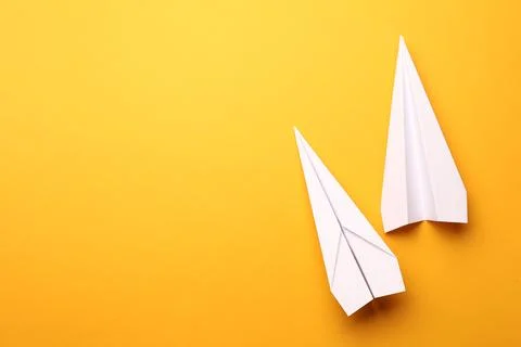 Handmade white paper planes on yellow background, flat lay. Space for text Stock Photos