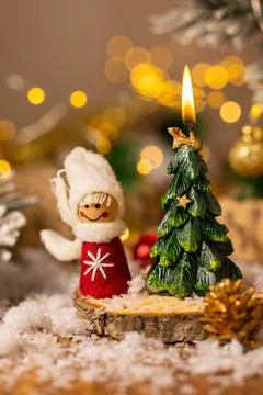 Handmade winter figurine beside burning Christmas tree candle on snowy wood.. Fotos de archivo