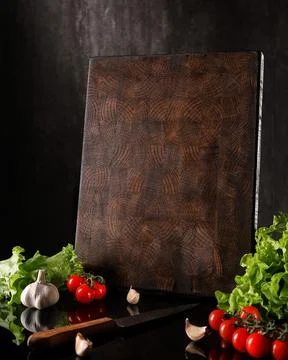 Handmade wooden chopping board with fresh vegetables on a dark background. space Stock Photos