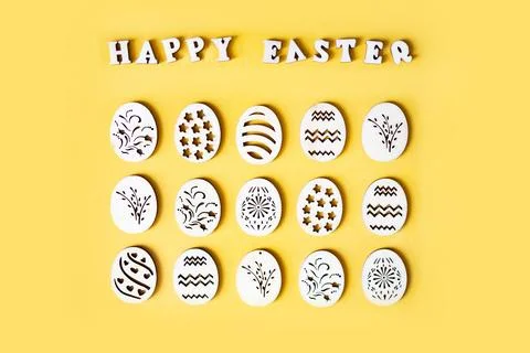 Handmade wooden Easter eggs with patterns on a yellow background. 库存照片