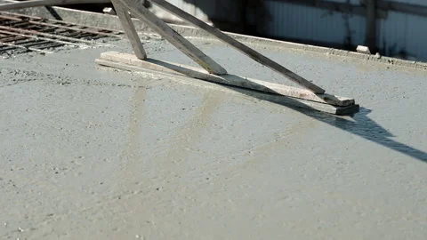 Handmade wooden leveling tool resting on freshly poured concrete slab, Close-up Stock Footage 306446237