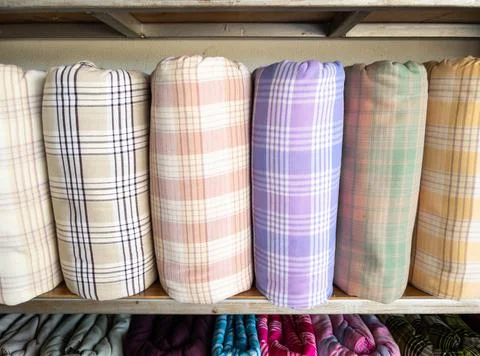 The handmade woven silk rolls with the plaid pattern are on shelves. Stock Photos
