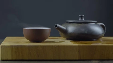 Handmade yixing clay teapot for tea with hot tea in a bowl on a wooden board. Stock Footage 120239200