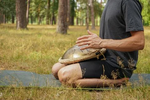 A handpan is placed on the forest floor, accompanied by bright orange sticks. Foto stock